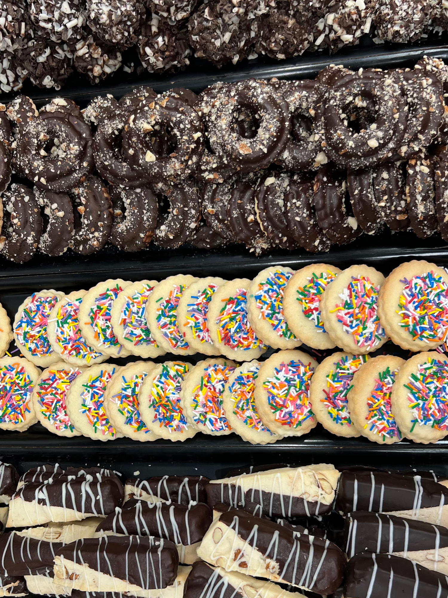 Assorted cookies including um Balls, Peanut Butter Rings, Raspberry Cream, and Almond Vienna on trays